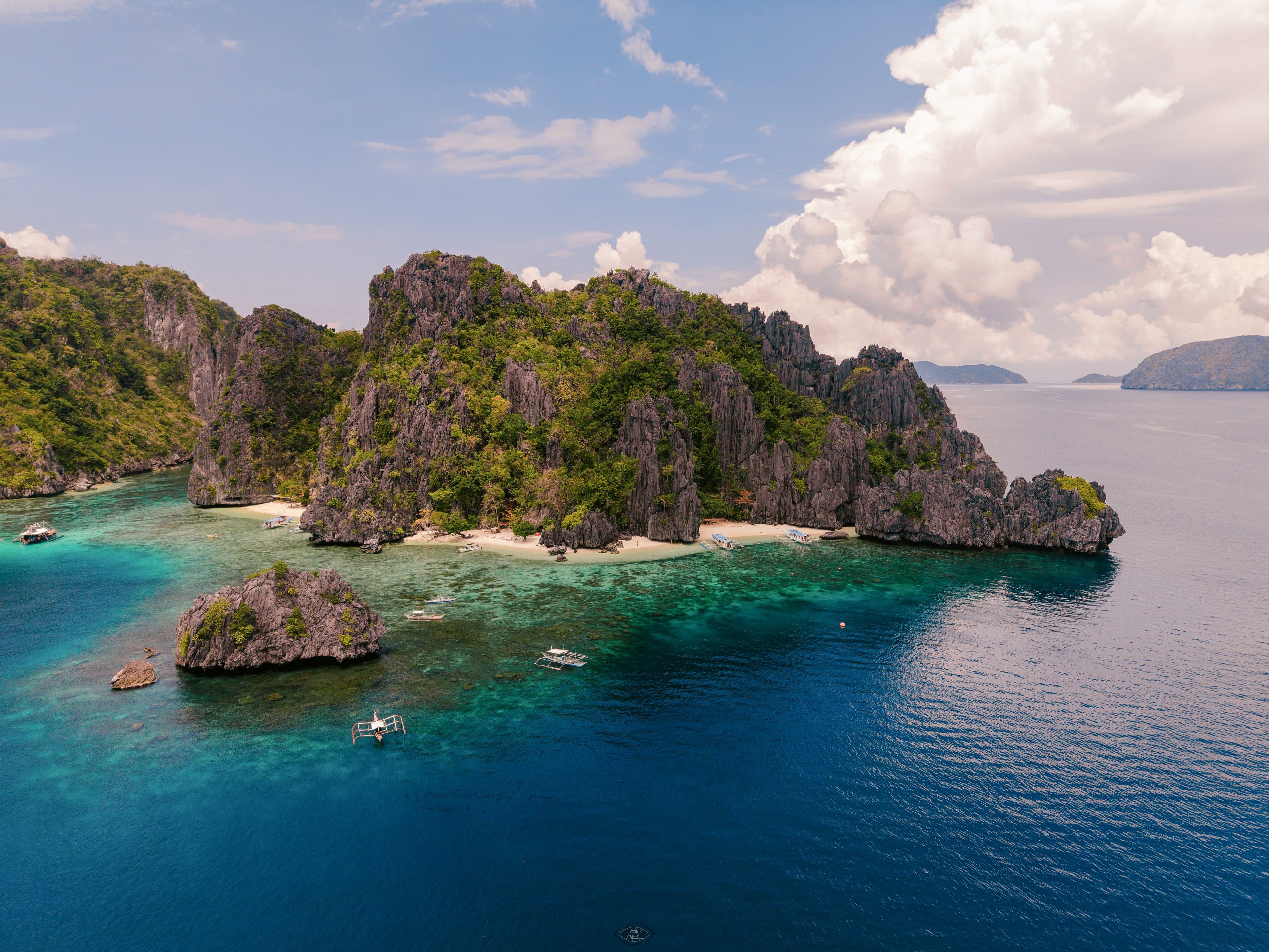 Aerial view of a limestone island and turquoise water in Bacuit Bay, El Nido, Palawan